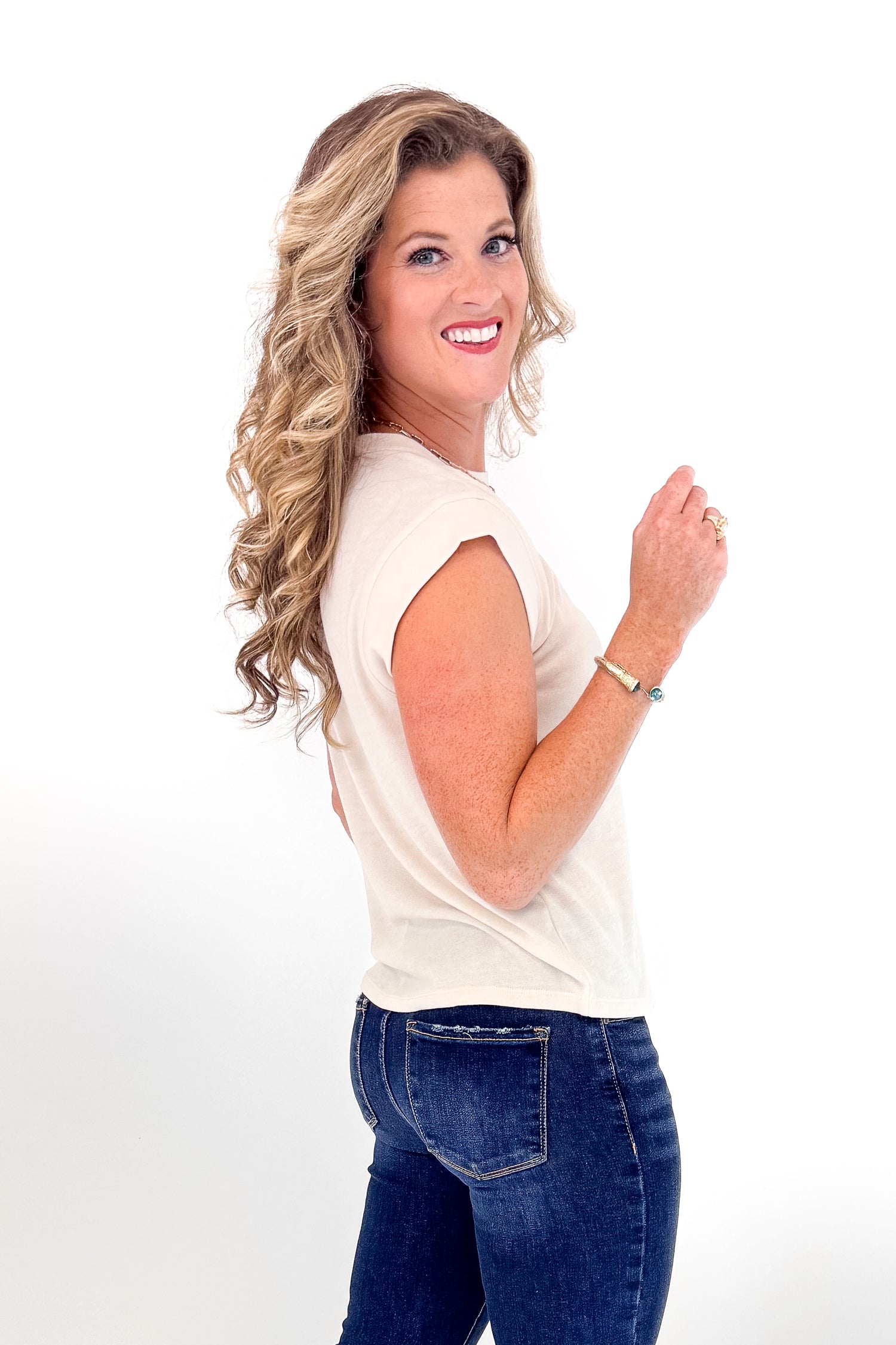 Woman wearing a white sleeveless top and blue jeans on a white background