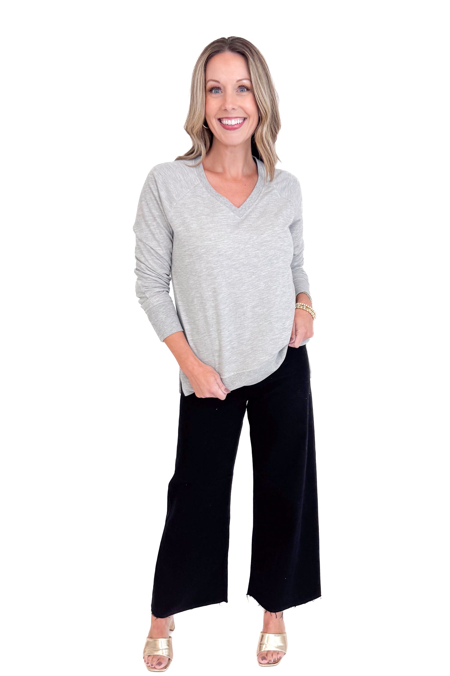Woman wearing a gray sweater and black pants on a white background