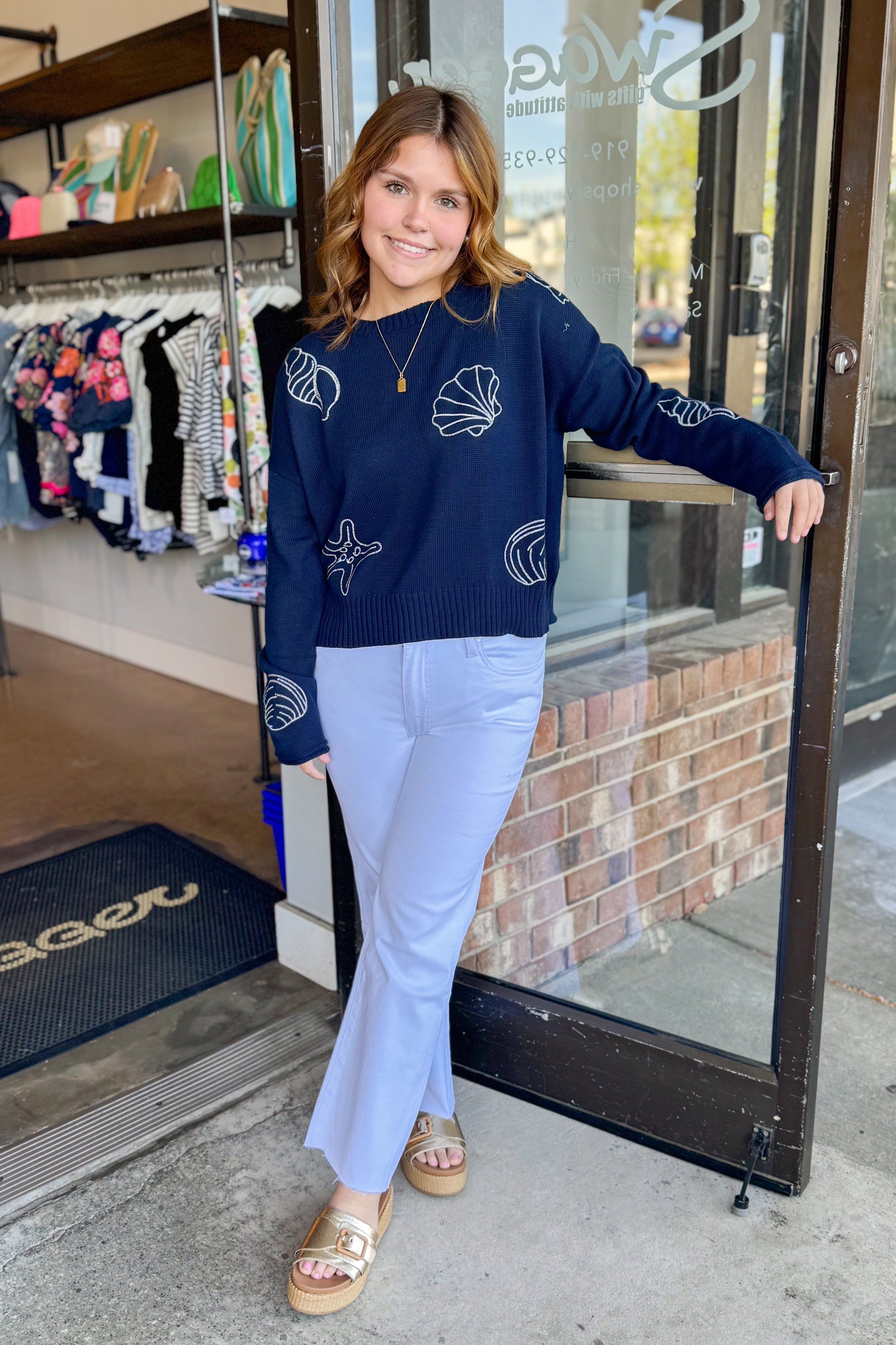 Front view of woman wearing True Navy Paradise Reef Sienna Sweater by Z Supply with jeans standing outside of Swagger Boutique.