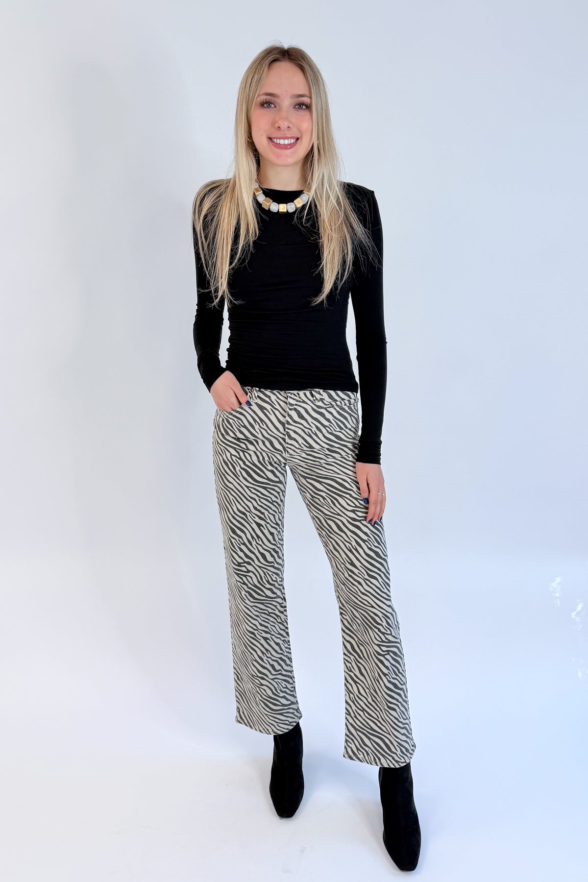 Front view of woman wearing Swagger Boutique’s top with Zebra Straight Leg Jeans by Just Black Denim against white studio background.