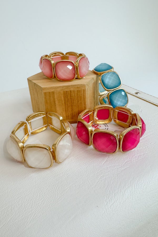 Colorful bracelets with gold accents on a white surface