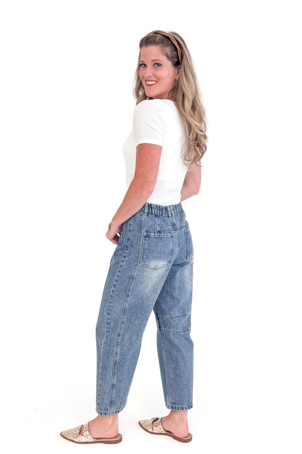 Woman wearing blue jeans and a white top on a white background