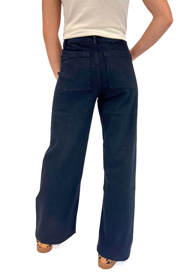 Woman wearing a beige t-shirt and black jeans on a white background