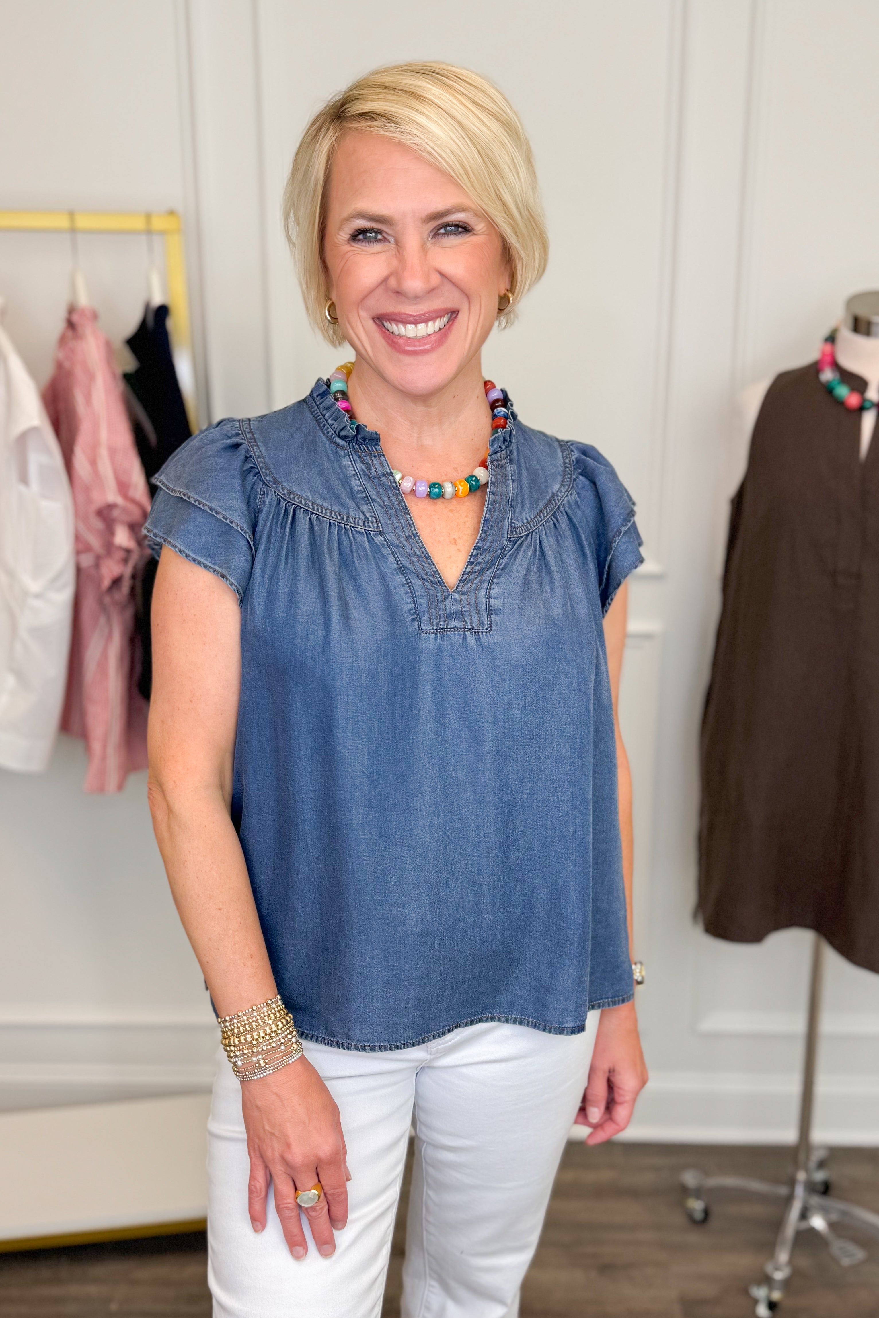 Woman wearing a blue top and white pants in a clothing store setting