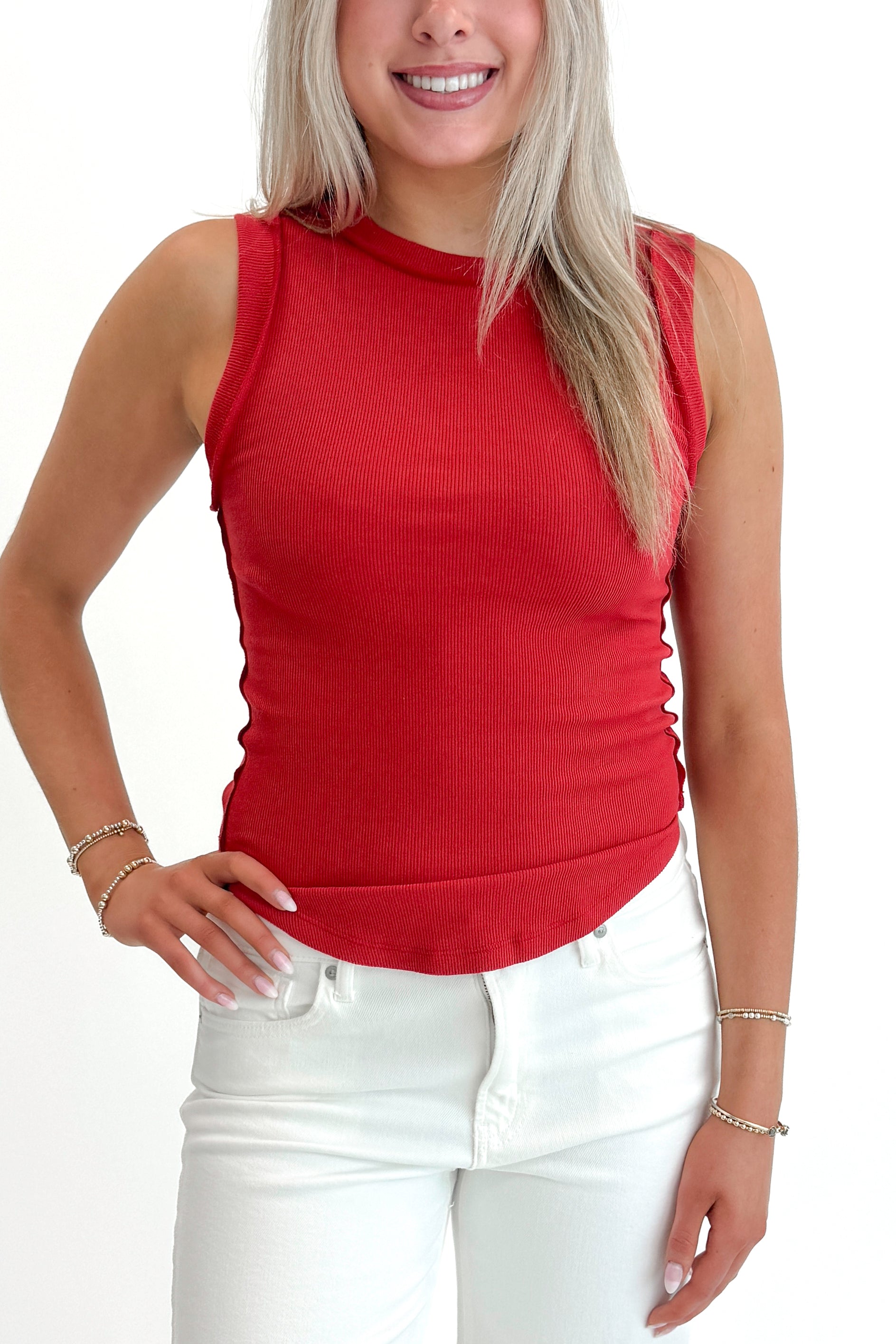 Front detail view of woman wearing Red Round Hem Ribbed Tank with jeans against white studio background.