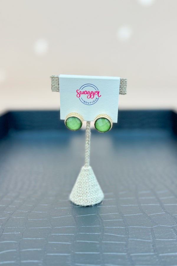 Green earrings on a stand with &