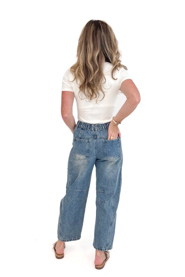 Woman wearing a white top and blue jeans on a white background