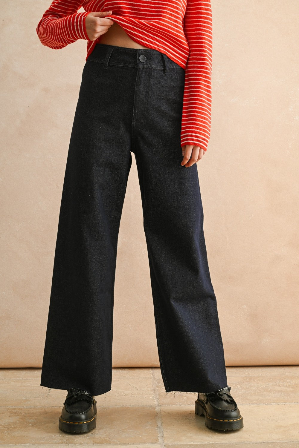 Front view of woman in a studio wearing Dark Indigo Wide Leg Jeans and print top with a tan background.