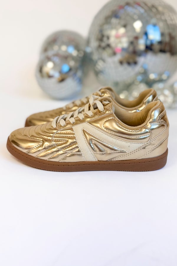 Gold sneakers with white accents on a white background