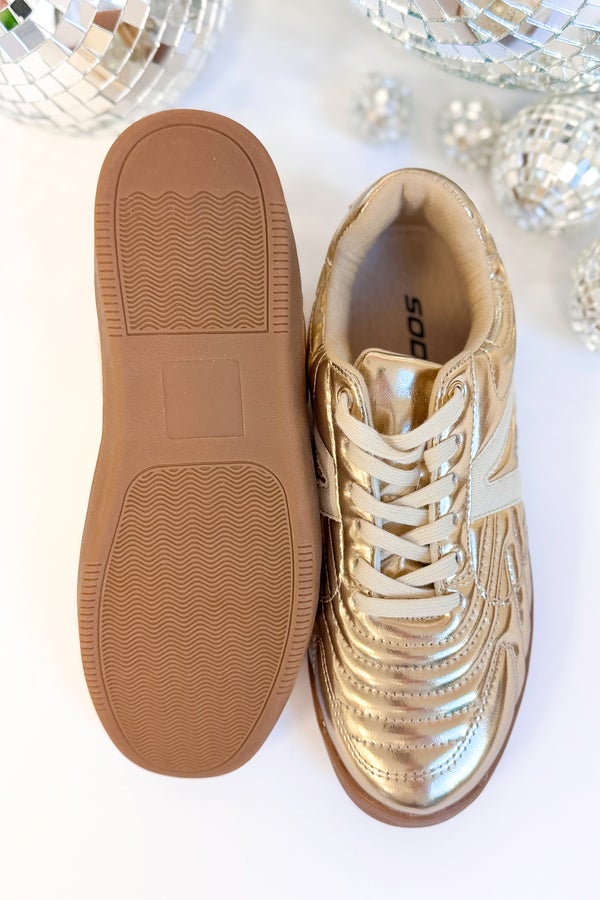 Gold sneakers with brown soles on a white background