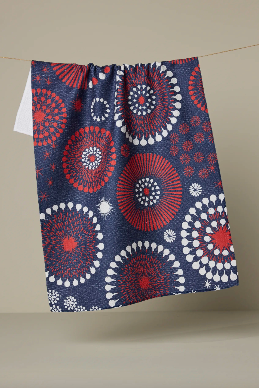 Navy blue towel with red and white circular patterns hanging on a line against a beige background