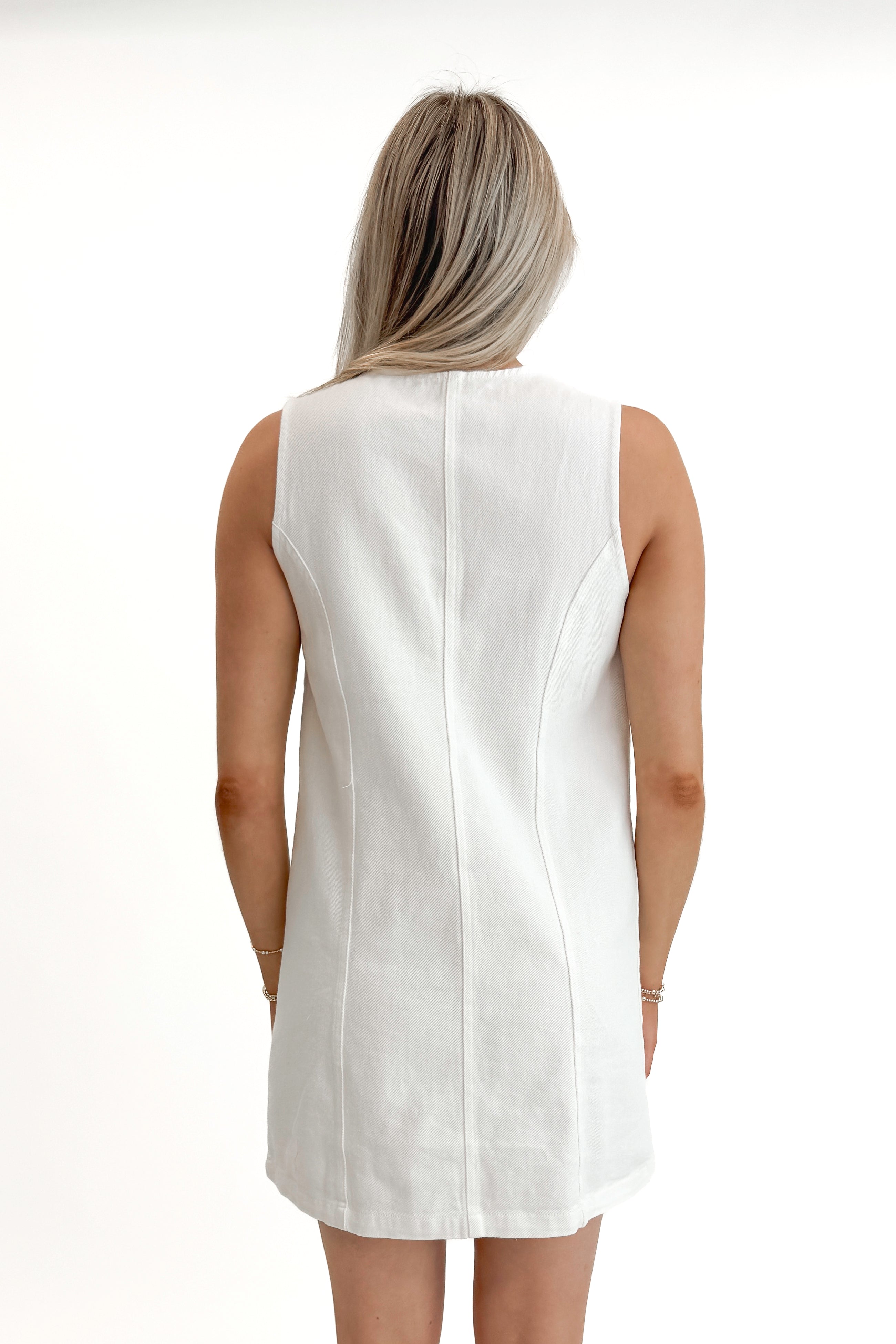 Back view of woman wearing White Denim Button Up Dress against white studio background.