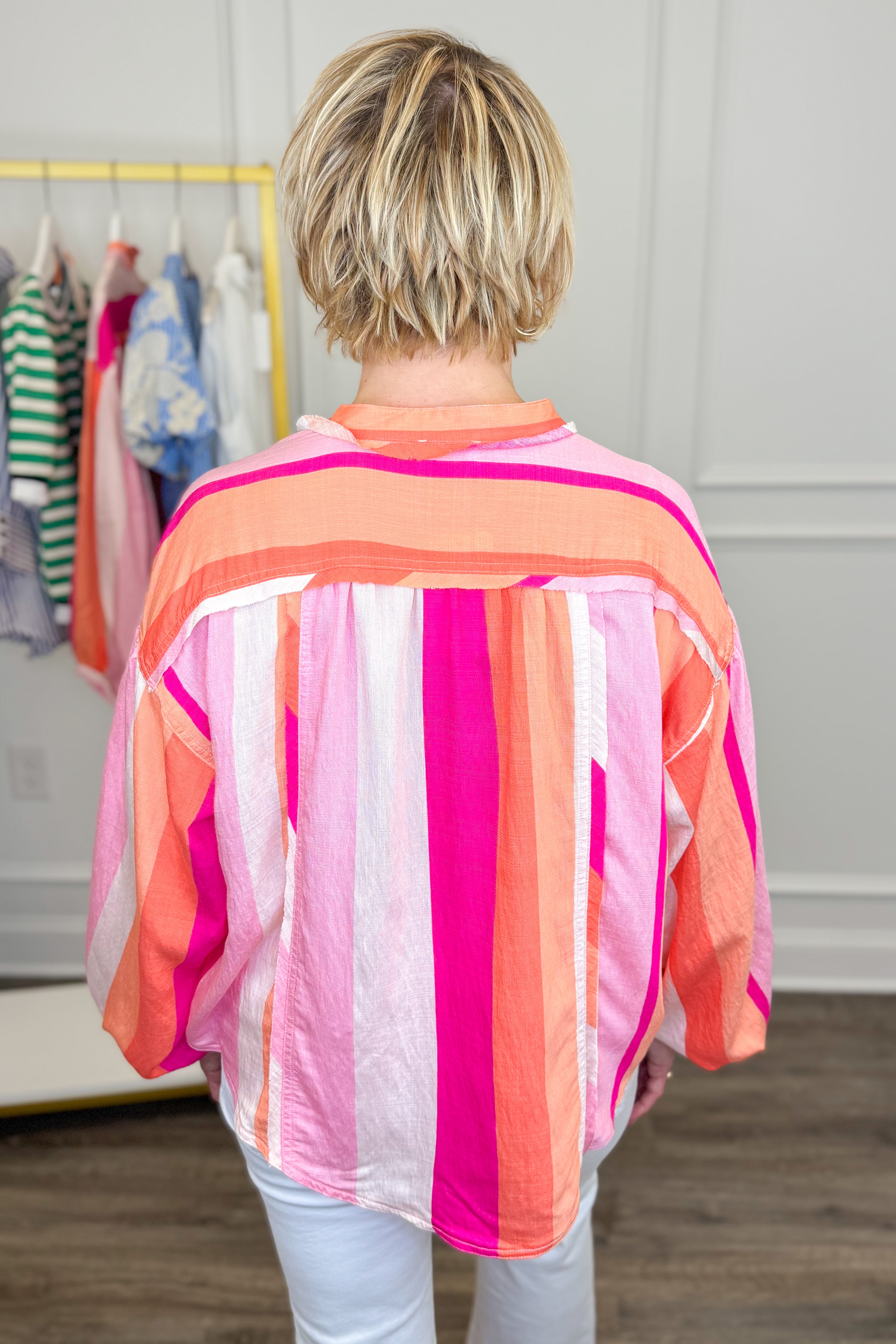 Person wearing a colorful striped shirt in a clothing store.
