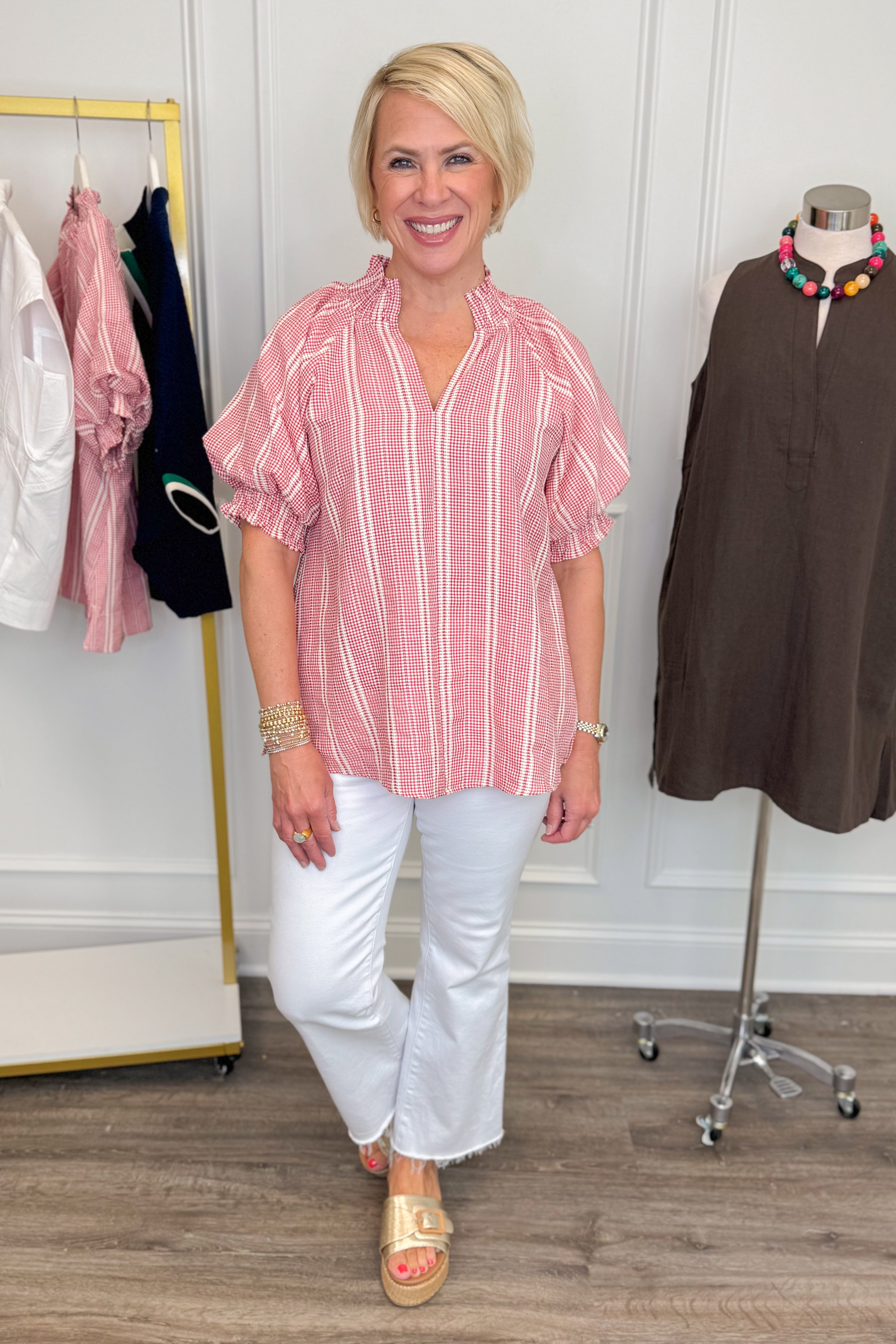 Woman wearing a red and white striped blouse with white pants in a clothing store.