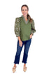 Woman wearing a green top with floral sleeves and blue jeans on a white background