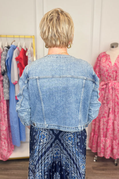 Back view of woman wearing Medium Wash Collarless Denim Jacket by Just Black Denim with top and skirt. 