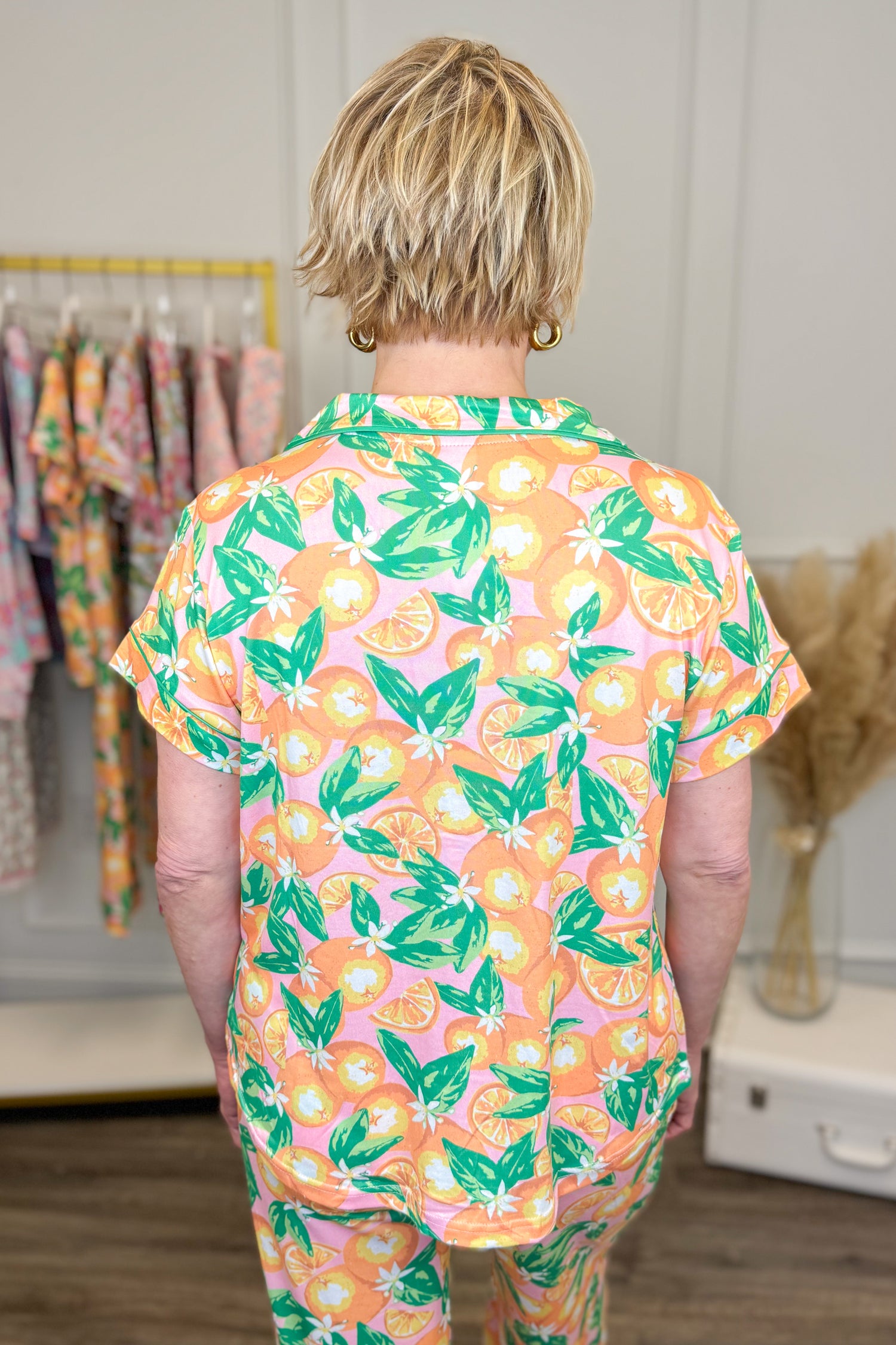 Child wearing a colorful pajama set with fruit pattern in a room.