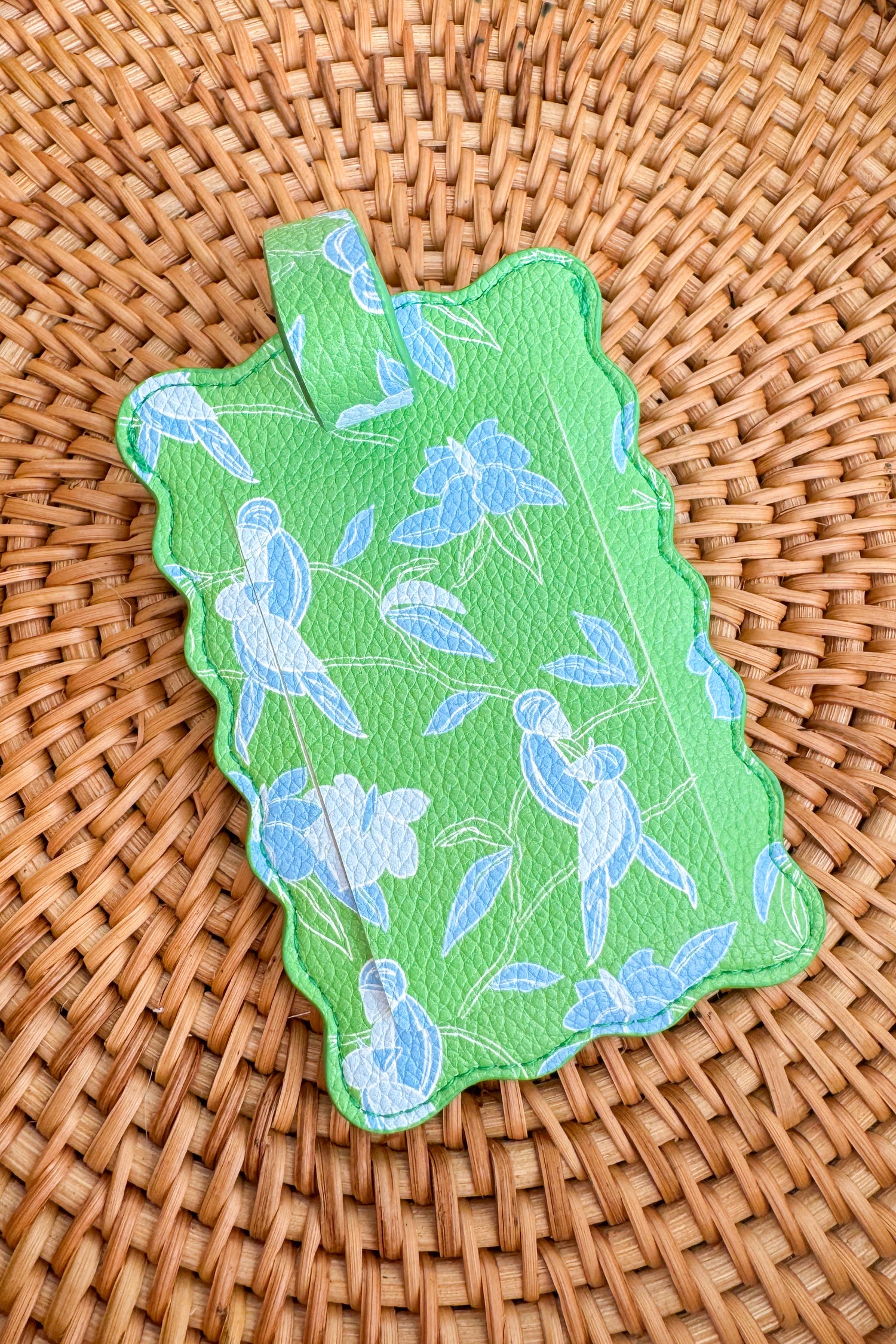 Green decorative item with blue floral patterns on a woven surface