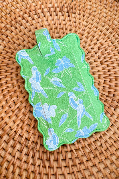 Green decorative item with blue floral patterns on a woven surface