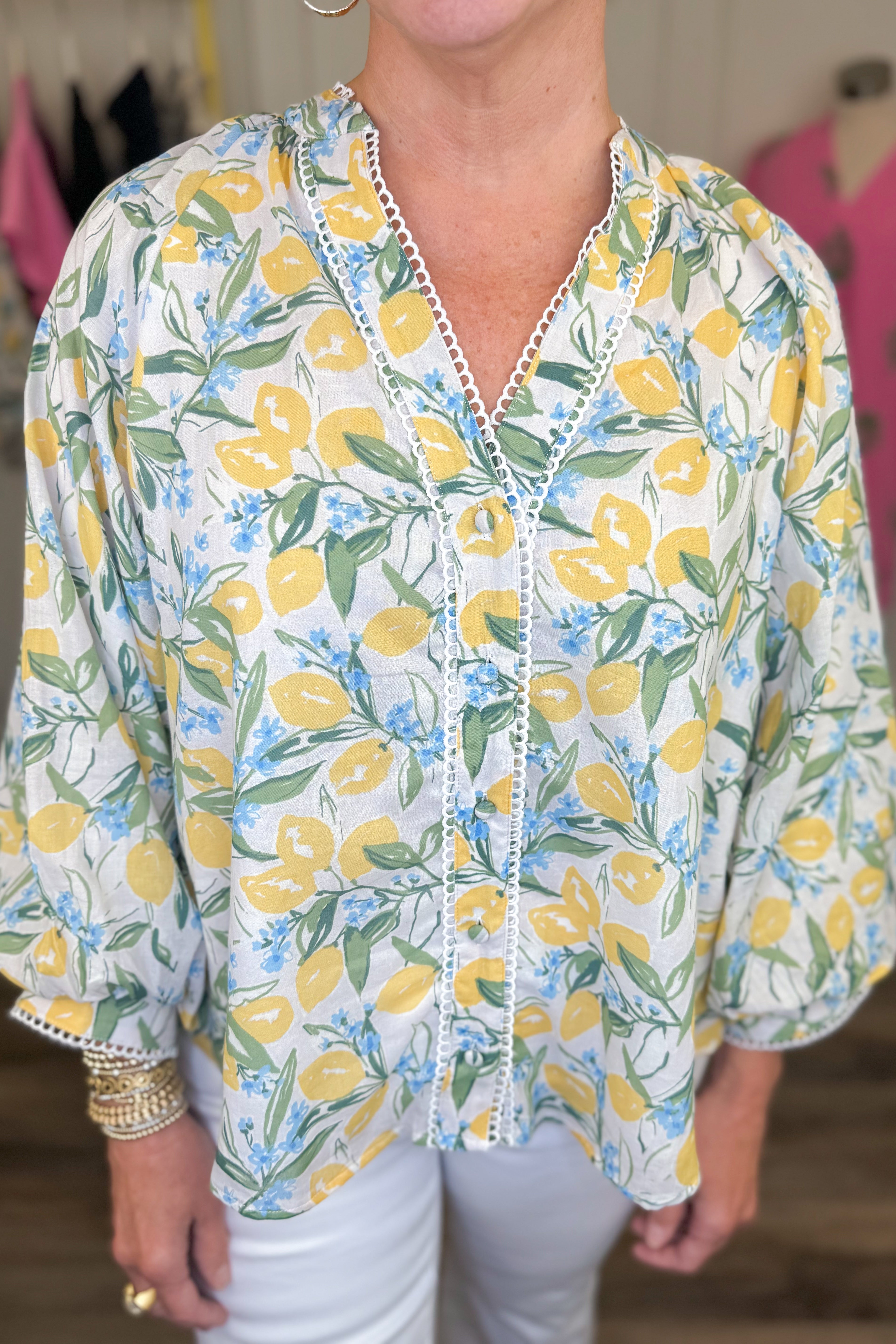 Front detail view of woman wearing Swagger Boutique’s Yellow &amp; Blue Lemon Print 3/4 Sleeve Top with jeans with clothes around.