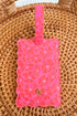 Pink textured luggage tag with a brand logo on a wicker surface