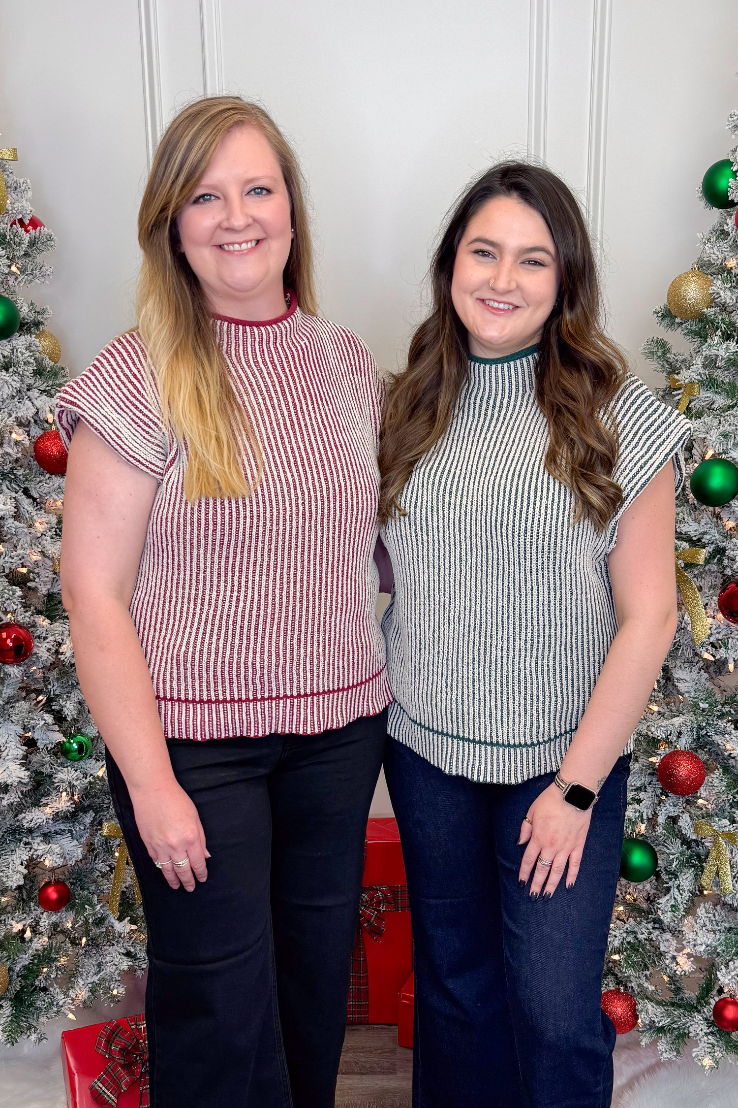 Two women standing in front of Christmas trees wearing matching outfits.