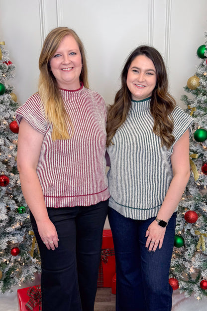 Two women standing in front of Christmas trees wearing matching outfits.