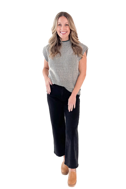 Front view of woman wearing sweater with jeans against white studio background.