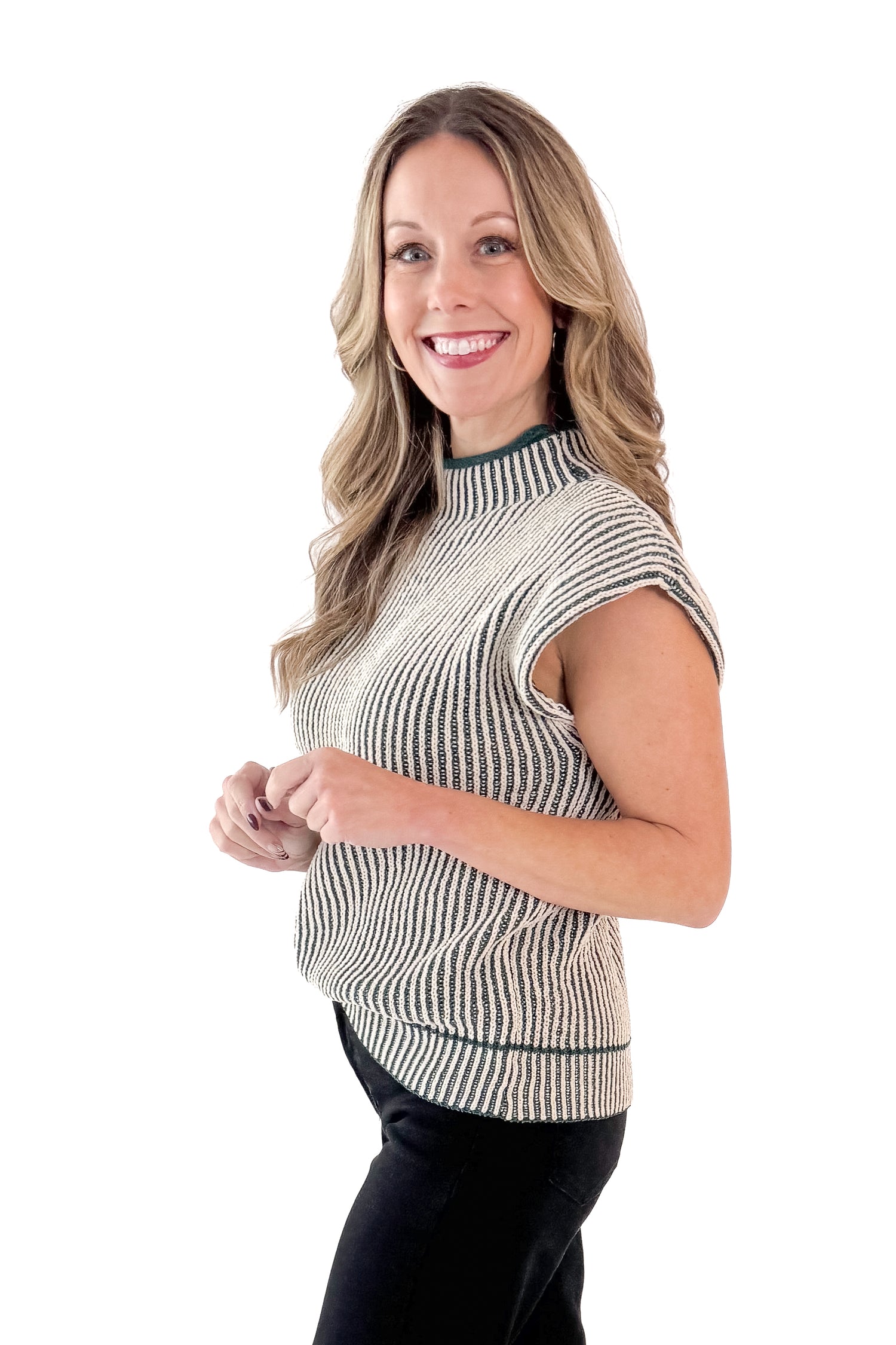 Side view of woman wearing sweater with jeans against white studio background.