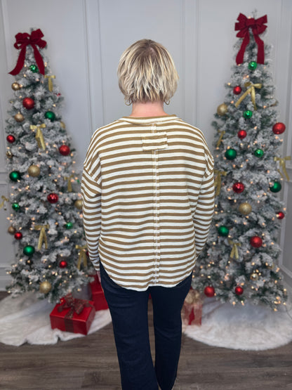 Person wearing a striped shirt standing in front of two decorated Christmas trees.