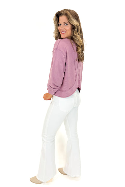 Side view of woman wearing Mauve Open Back Top with jeans against white studio background.