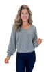 Front view of woman wearing Heather Grey Ribbed V-neck Banded Top with jeans against white studio background.