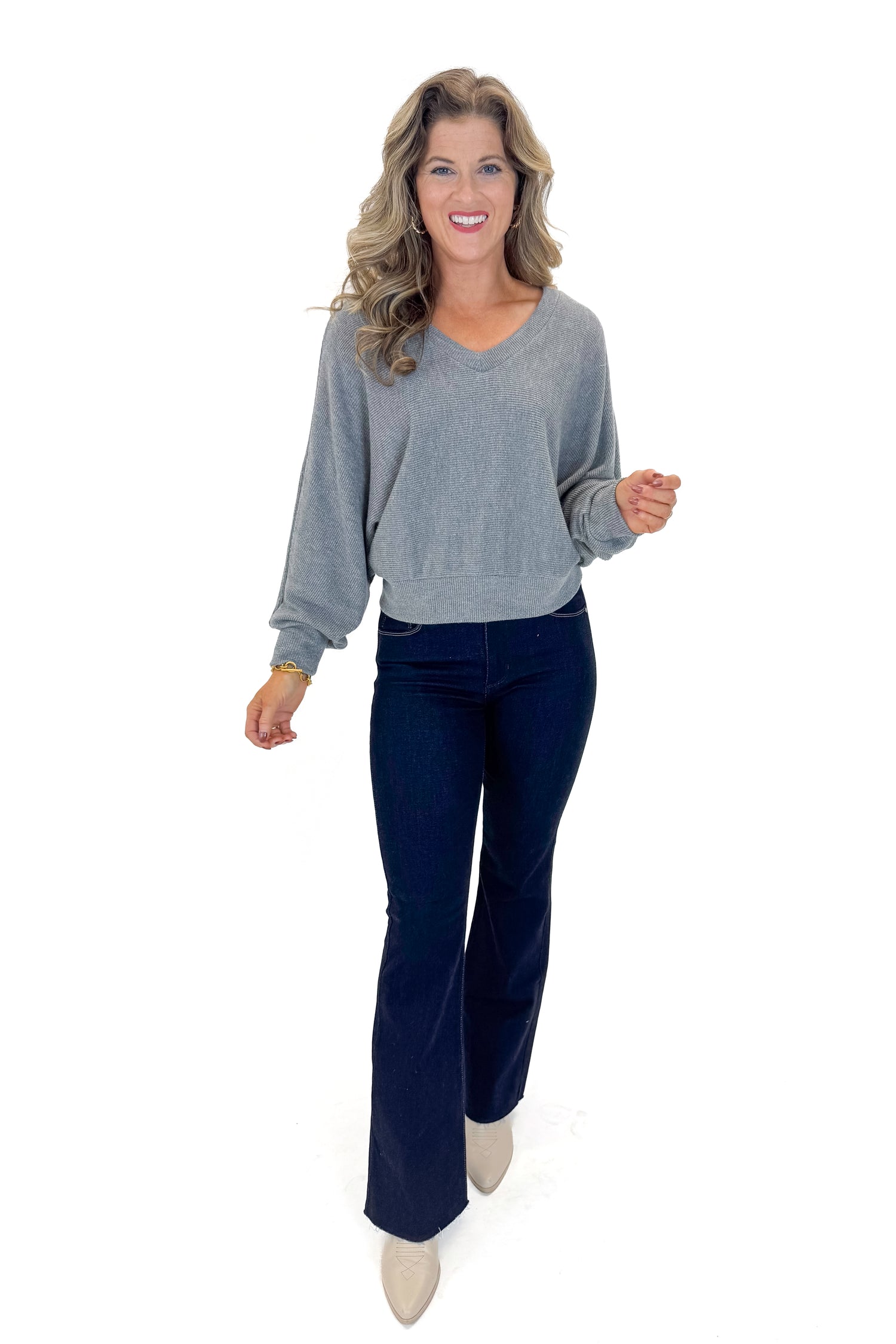 Front view of woman wearing Heather Grey Ribbed V-neck Banded Top with jeans against white studio background.