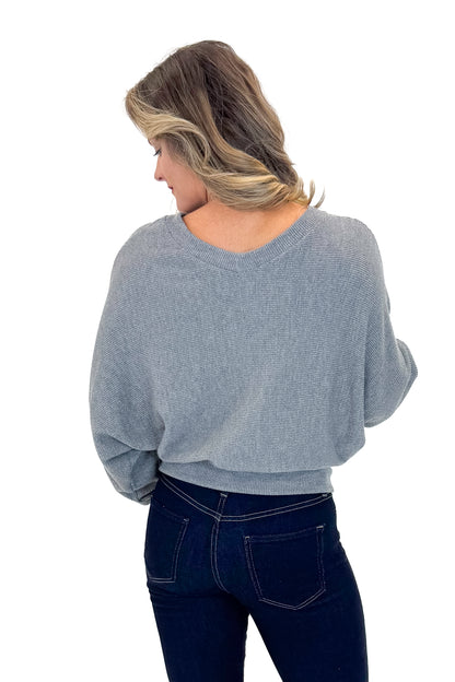 Back view of woman wearing Heather Grey Ribbed V-neck Banded Top with jeans against white studio background.