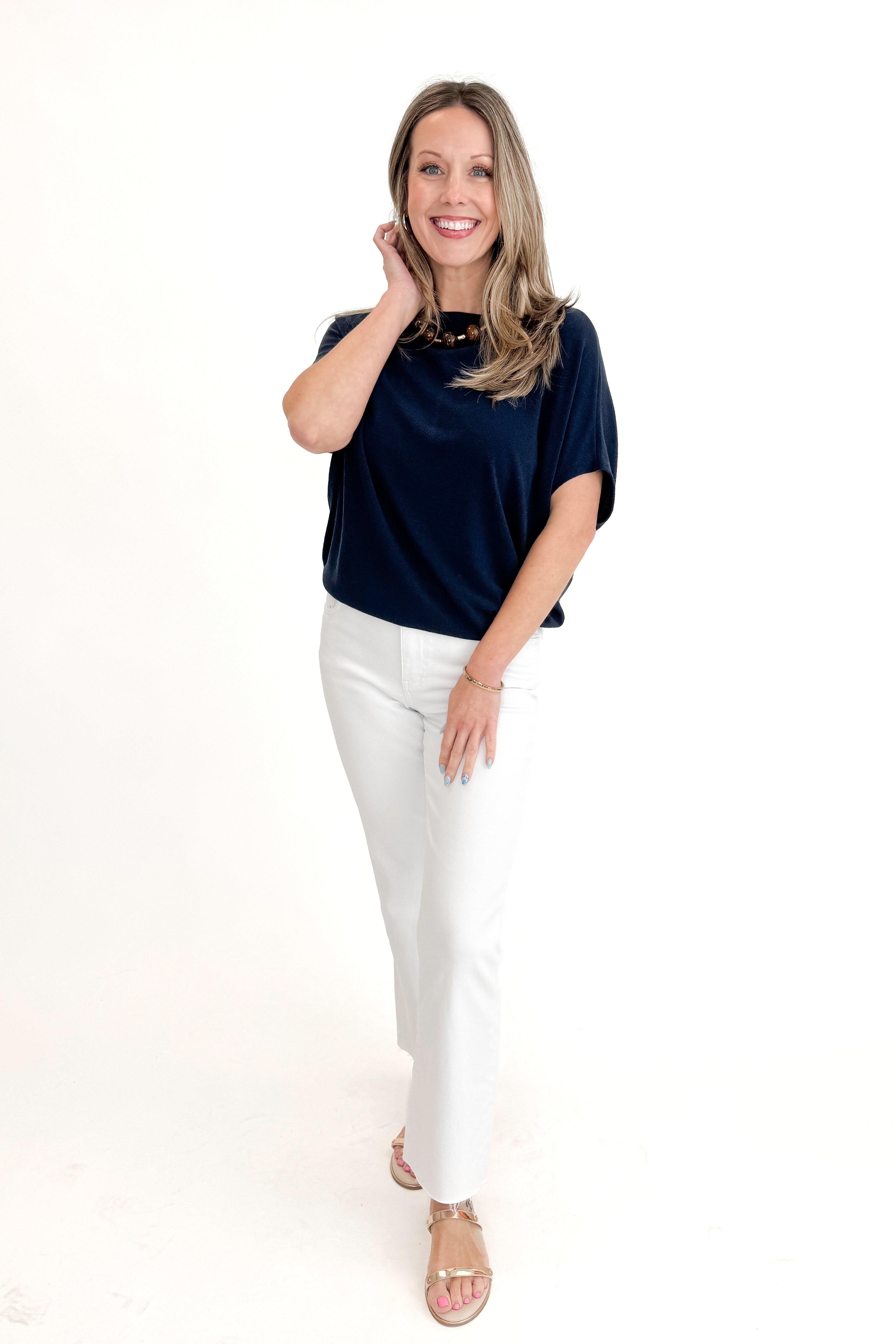 Front view of woman wearing Navy Dolman Sleeve Cocoon Top with jeans against white studio background.