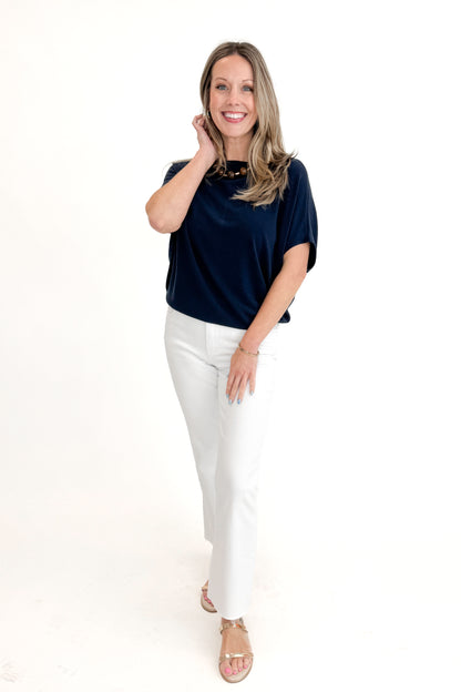 Front view of woman wearing Navy Dolman Sleeve Cocoon Top with jeans against white studio background.