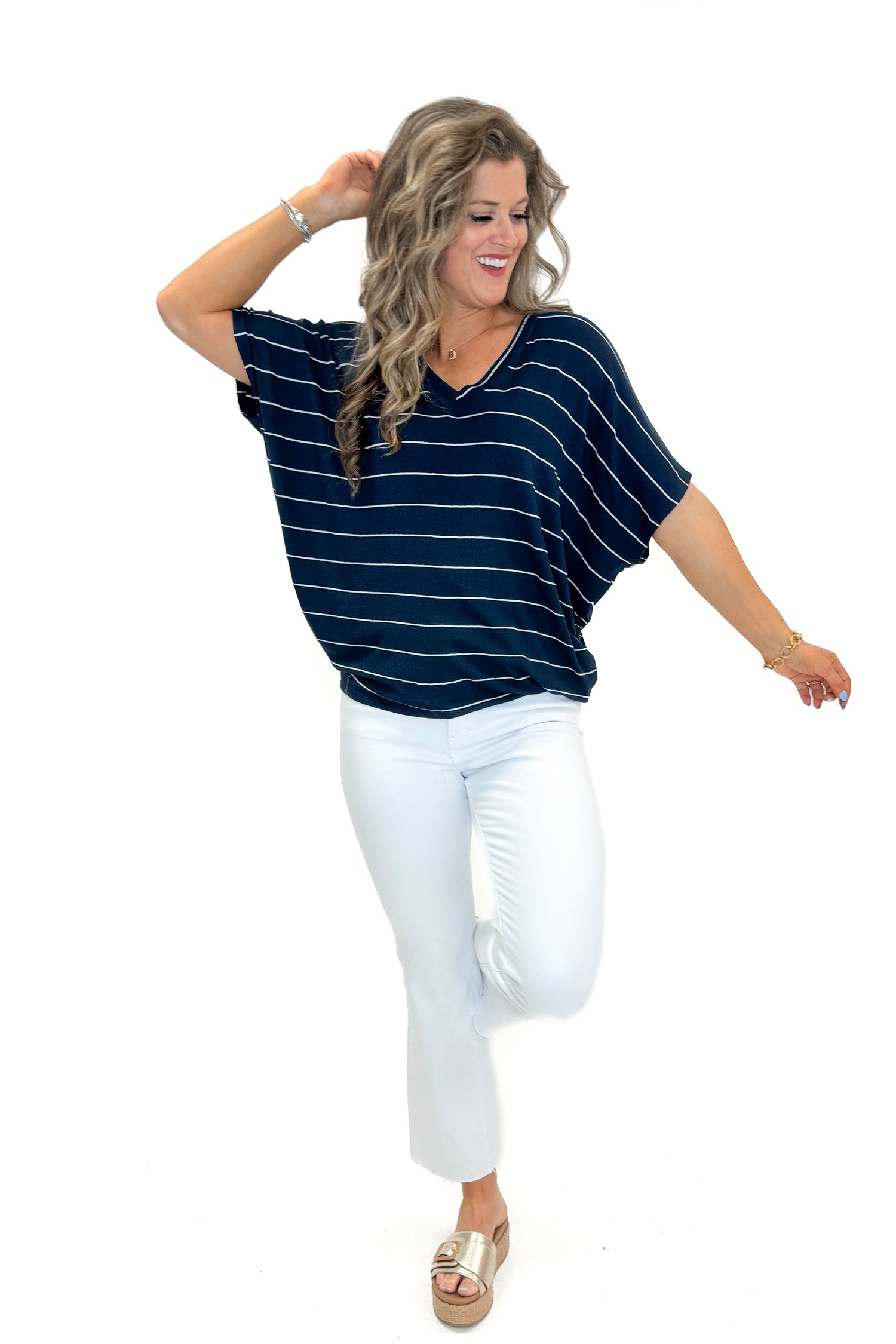 Front view of woman wearing Navy Striped Cocoon Top with jeans against white studio background.