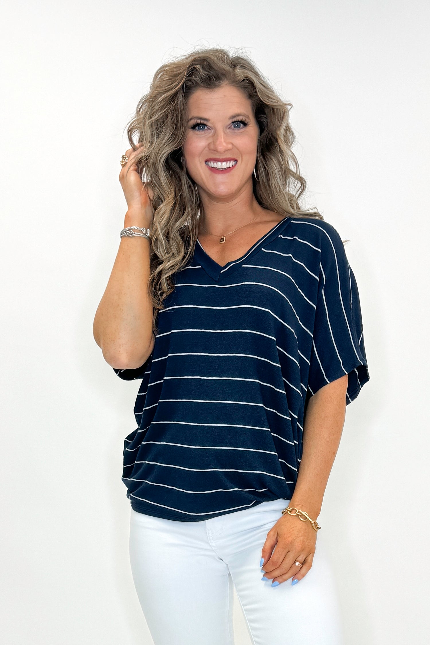 Front view of woman wearing Navy Striped Cocoon Top with jeans against white studio background.