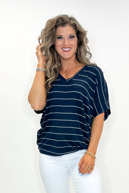Front view of woman wearing Navy Striped Cocoon Top with jeans against white studio background.