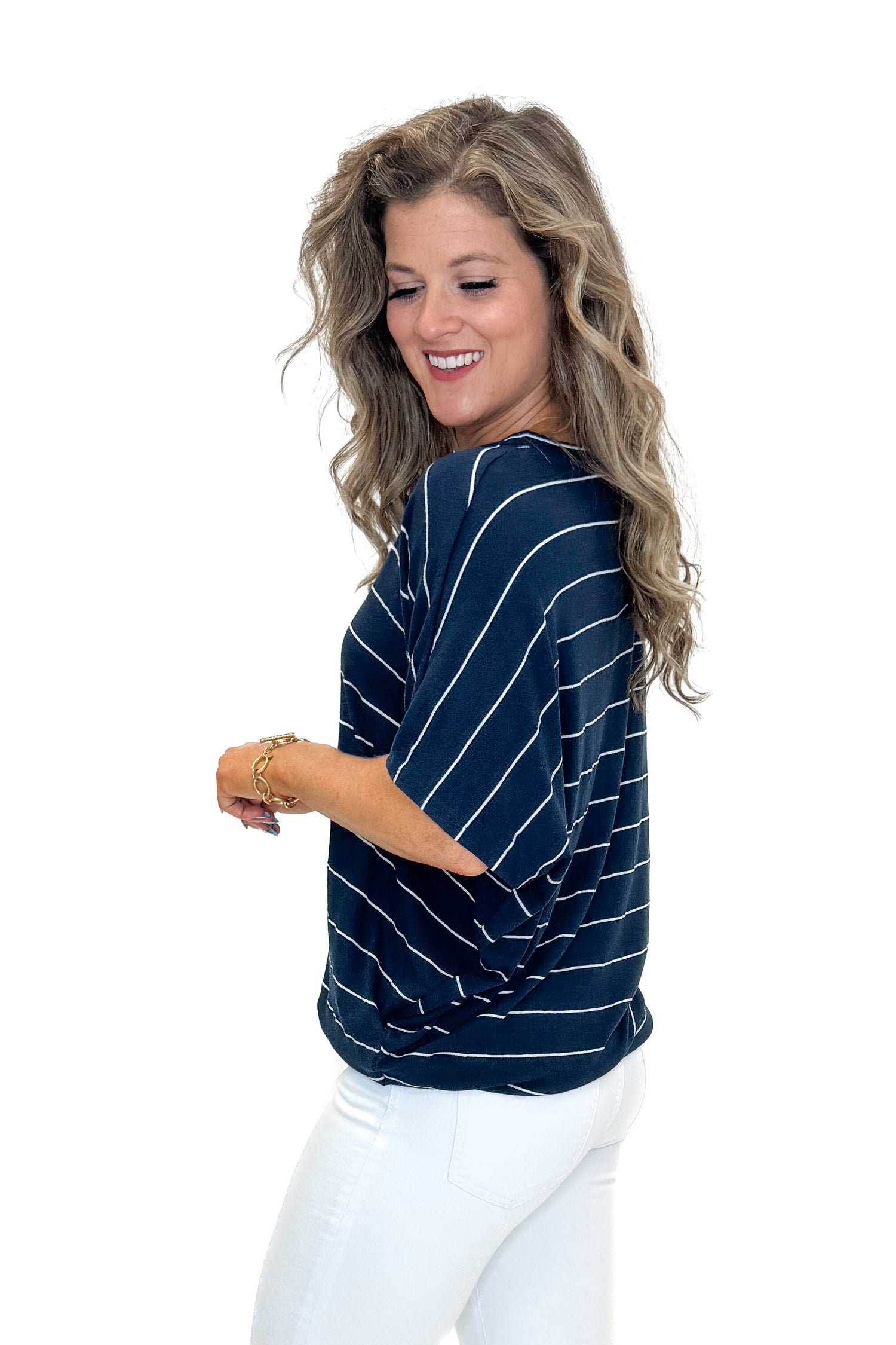Side view of woman wearing Navy Striped Cocoon Top with jeans against white studio background.