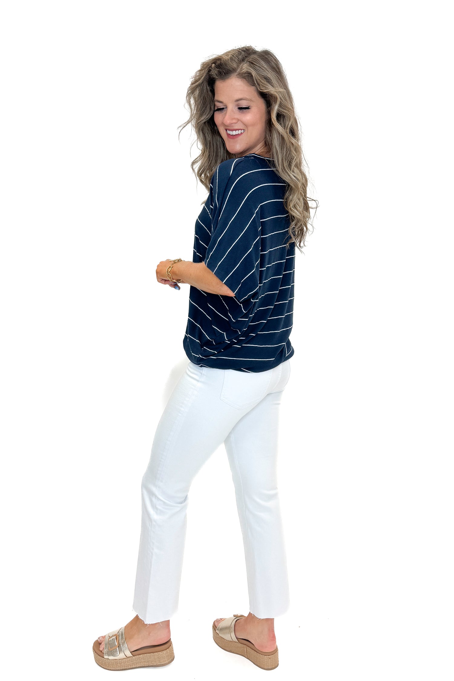 Side view of woman wearing Navy Striped Cocoon Top with jeans against white studio background.