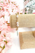 beaded bracelet with pearl detailing on a white surface with pink flowers in the background