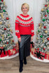 Woman wearing a red sweater with a Christmas tree and decorations in the background