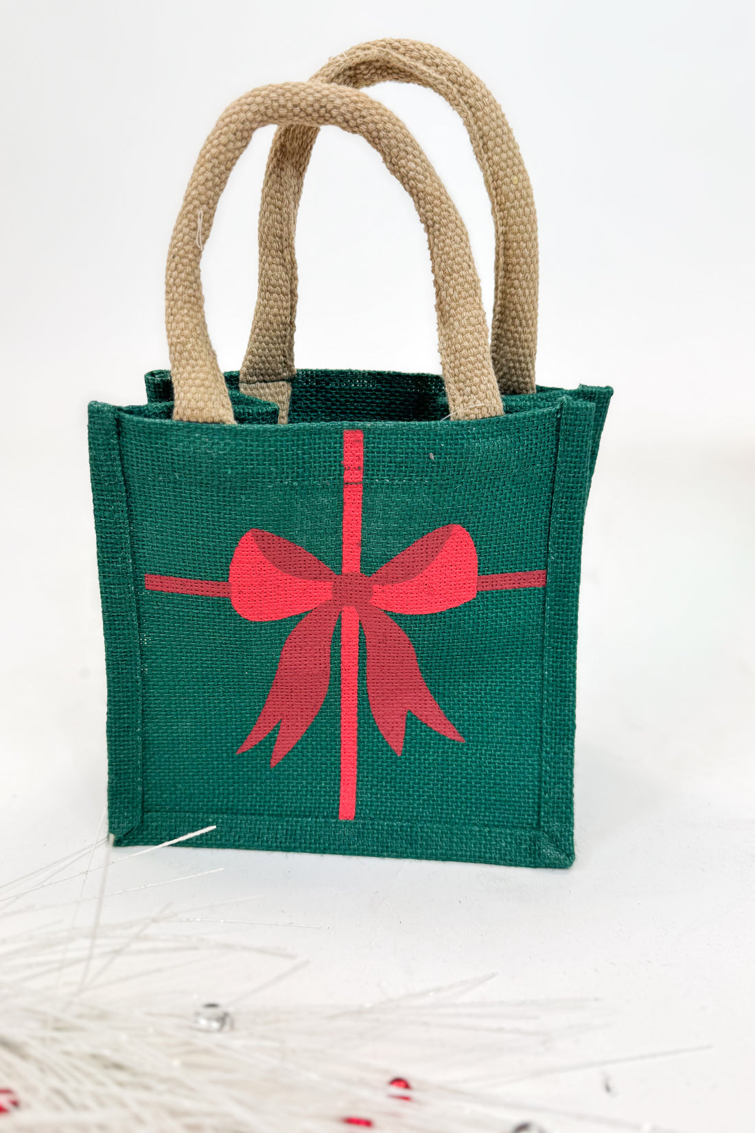 Green gift bag with a red bow design on a white background