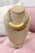 Gold necklace on a beige jewelry display stand with a pink background