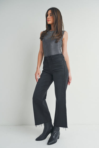 Stock photo of woman wearing washed black jeans and grey top against studio background.