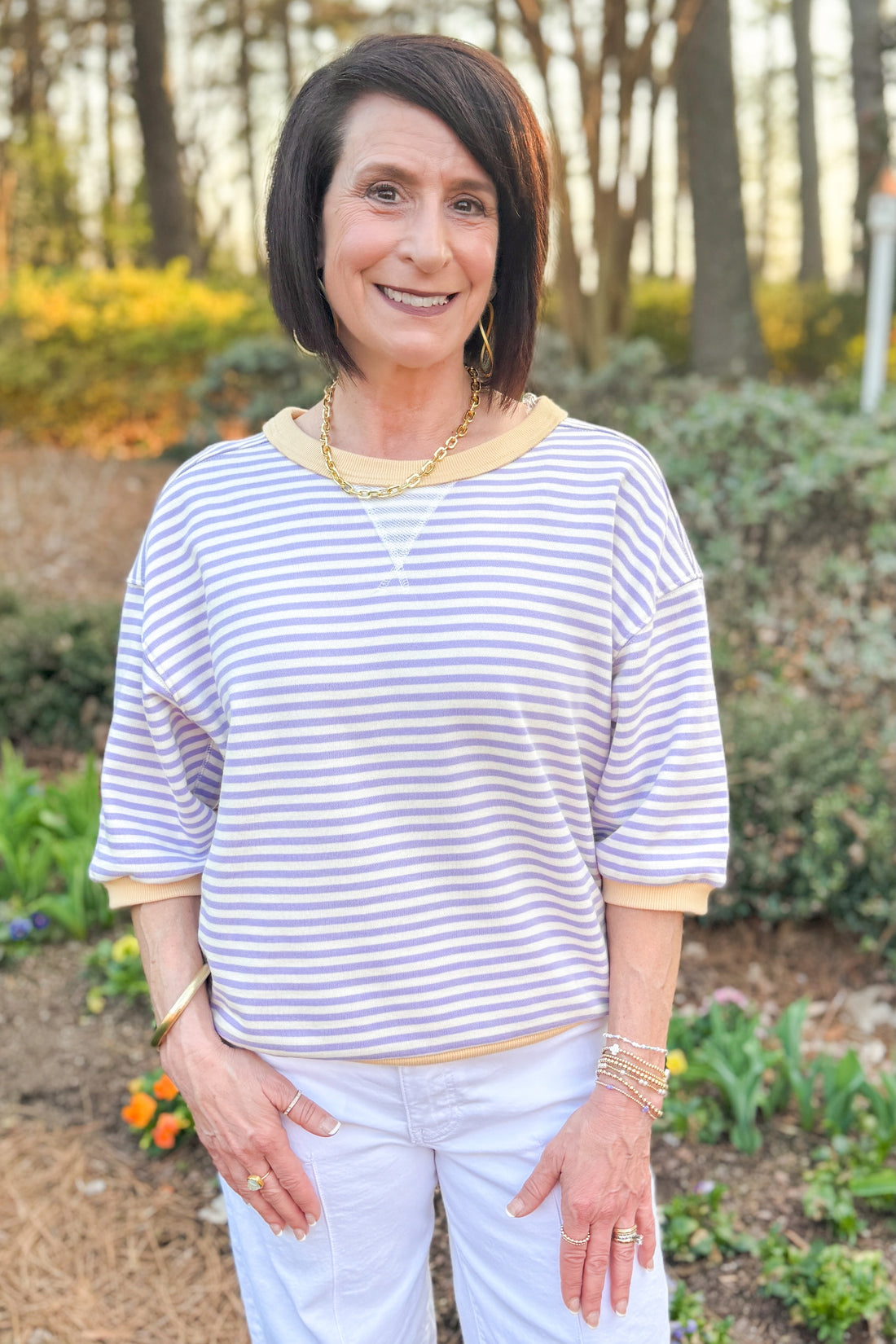 Front view of woman wearing Lavender &amp; Yellow Striped Half Sleeve Sweatshirt with jeans outside at a garden.