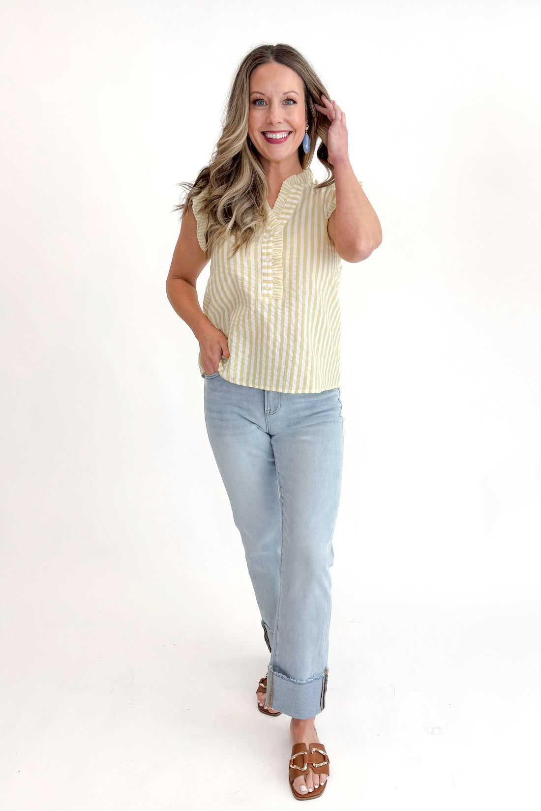 Front view of woman wearing Yellow Striped Flutter Sleeve Top with jeans against white studio background.
