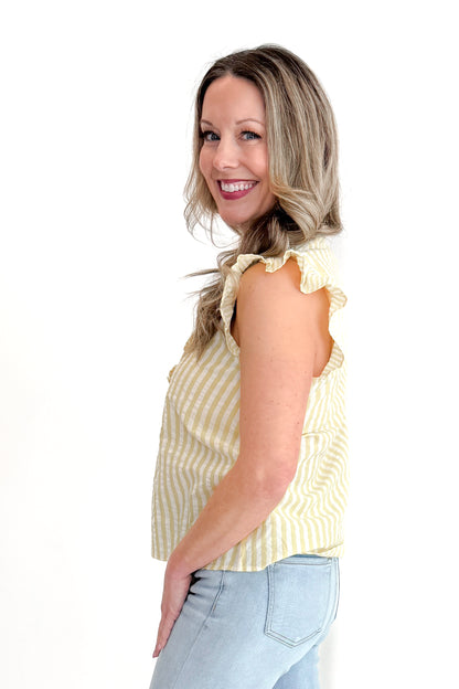 Side view of woman wearing Yellow Striped Flutter Sleeve Top with jeans against white studio background.