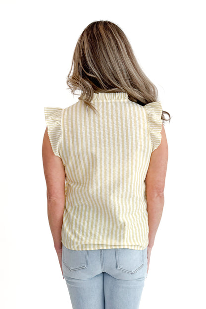Back view of woman wearing Yellow Striped Flutter Sleeve Top with jeans against white studio background.